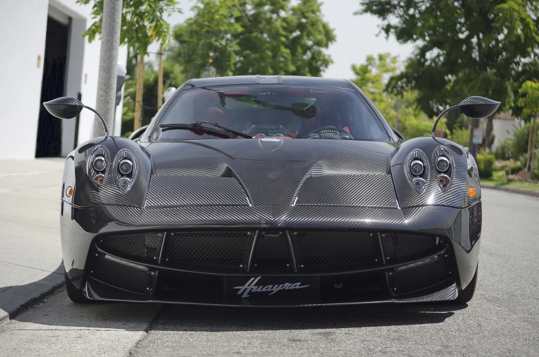 a gray sports car with chrome body kits driving down a road