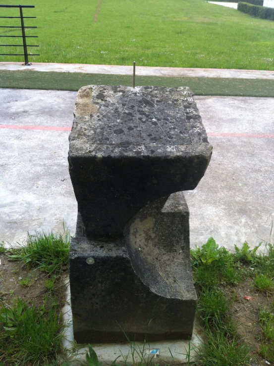 a black stone block with a green lawn behind it