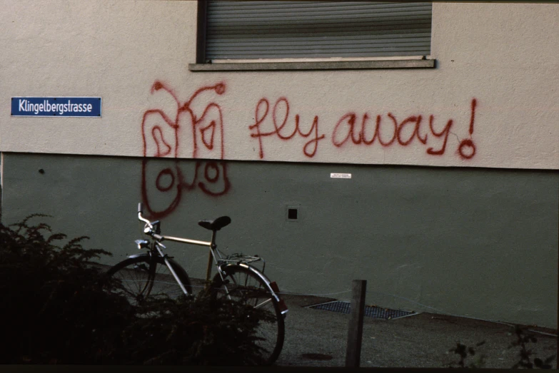 a bicycle parked next to a graffiti - covered building