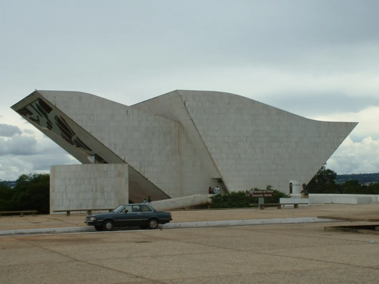 a car is parked in front of a large sculpture