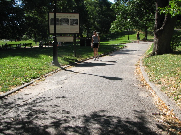 a man walking down a small road with a sign