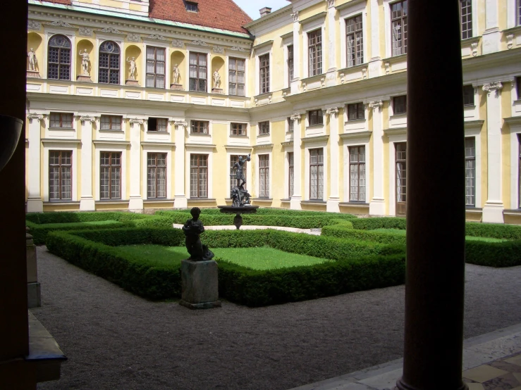 a large courtyard with bushes and a statue