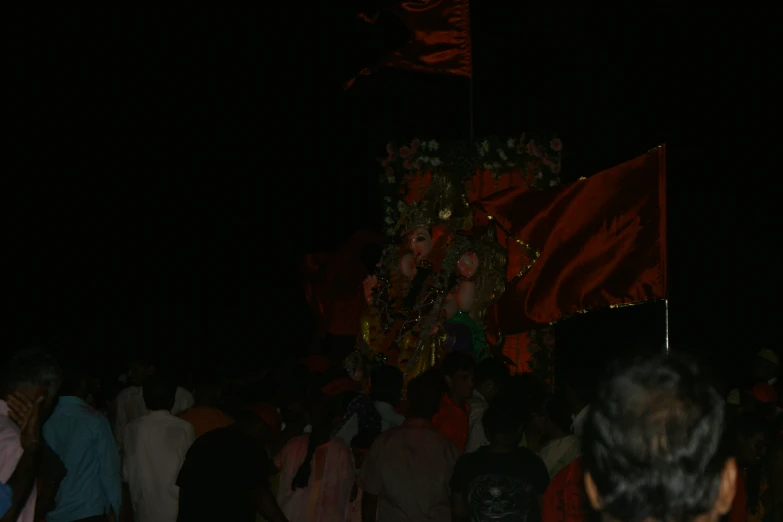 people walking in the dark with a statue in the background