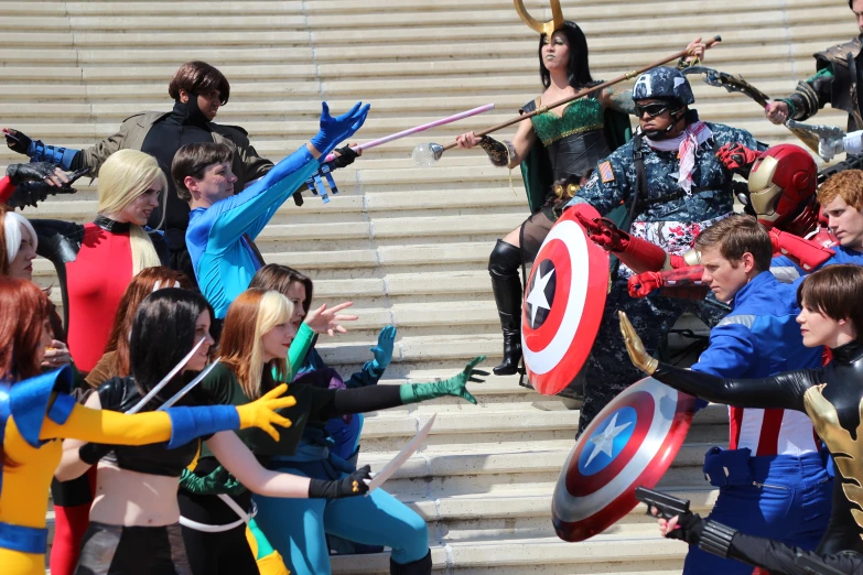 two groups of people dressed as captain america and queen mary pop in costume, posing on stairs