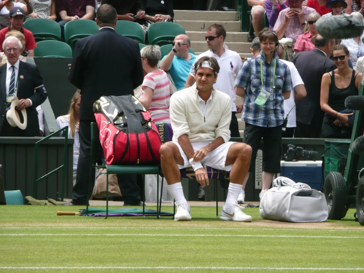 the tennis player is sitting on the court