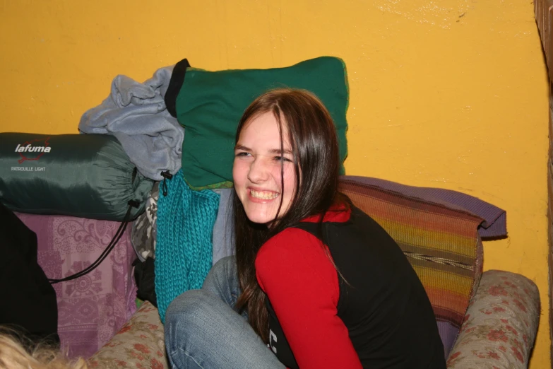 a smiling girl sitting next to some luggage