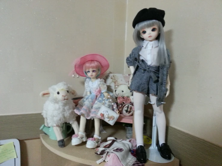 dolls sitting on a shelf with two dolls beside them