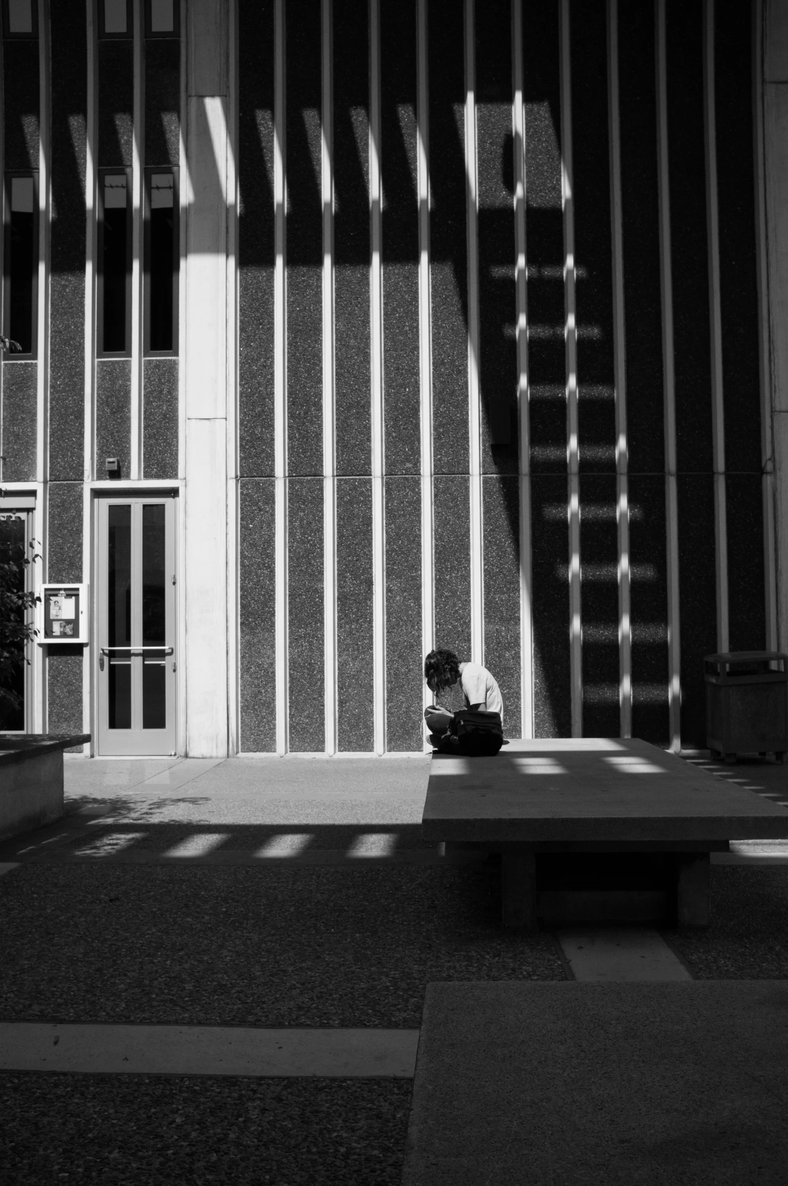 a person is sitting on a concrete bench in the sun