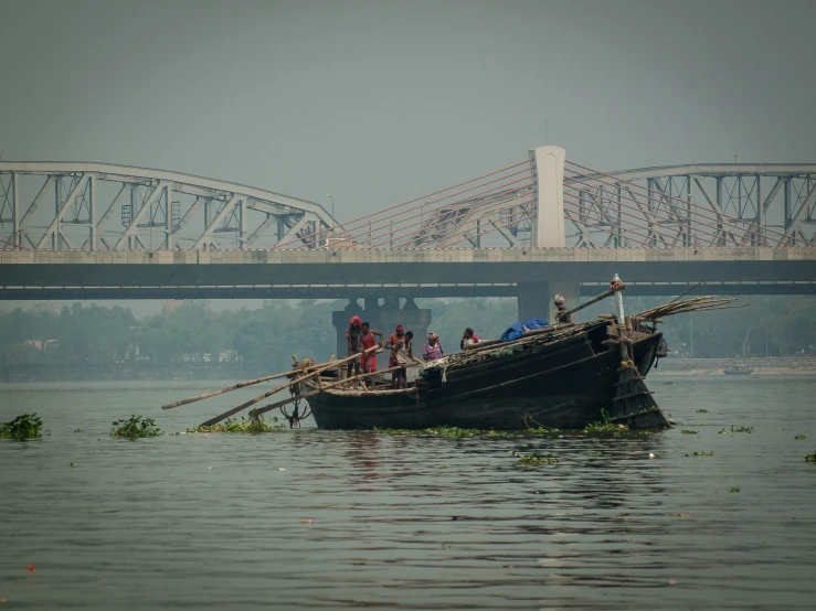 a boat full of people with an open bridge in the background