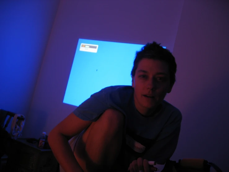 a person squatting next to a monitor in a room