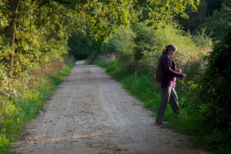 a man walking with an animal behind him and trees around