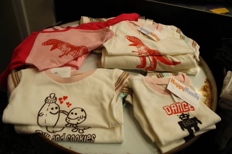 four baby girl's shirts sitting on top of a table