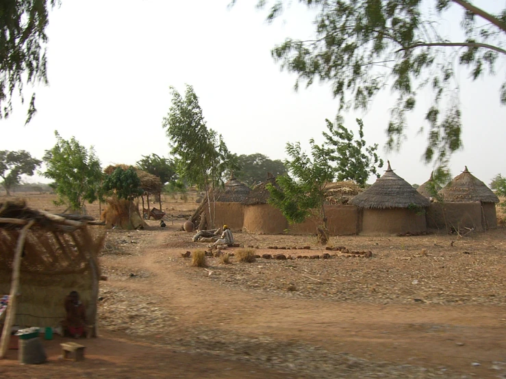 a dirt road with a small group of huts on the ground