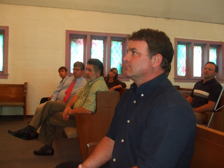 the group of men are sitting in the church together