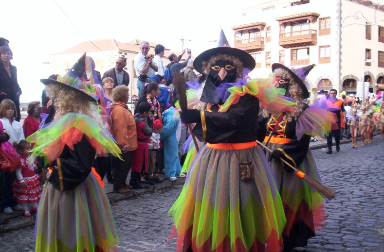 a group of people wearing costume walk down a cobblestone road