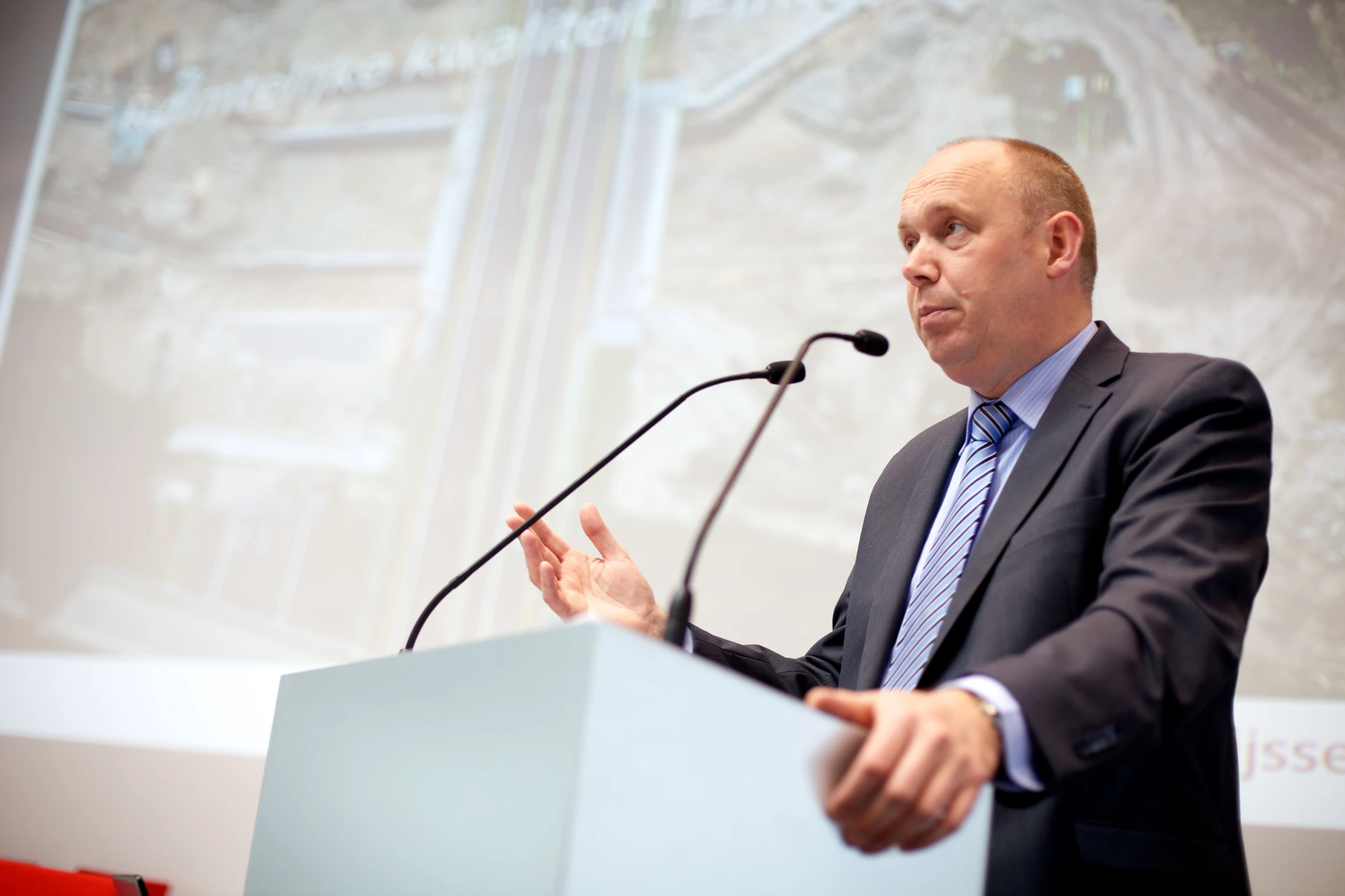 a man is speaking at a podium during a presentation