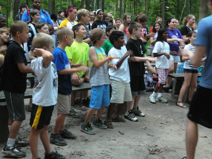 a group of children stand around and perform a tug of war