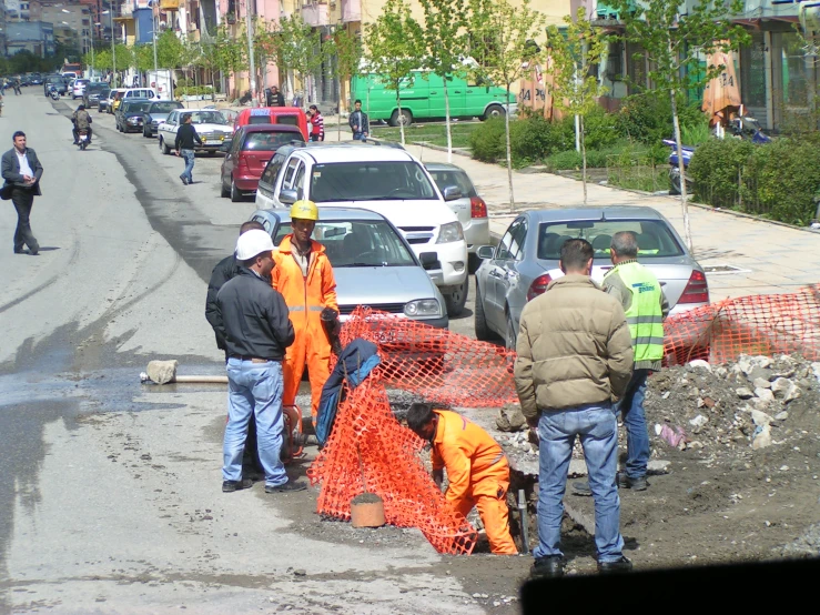 people work to repair road construction on a busy city street