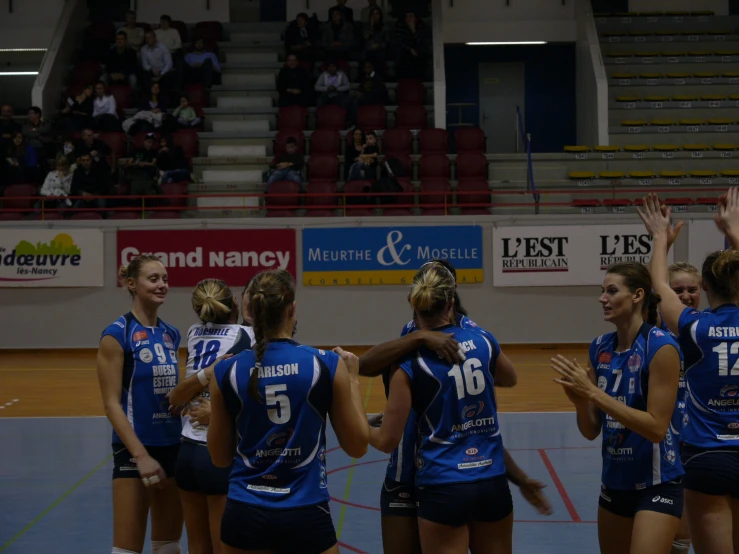 some volleyball players standing together with their arms in the air