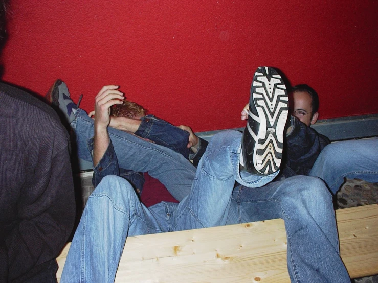 three men sitting in the corner one holding up his shoe