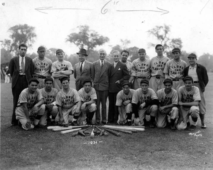 a baseball team is posing with a coach in uniform