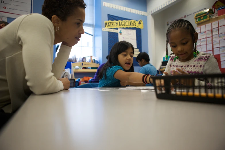 a teacher assisting a little girl writing with her older daughter