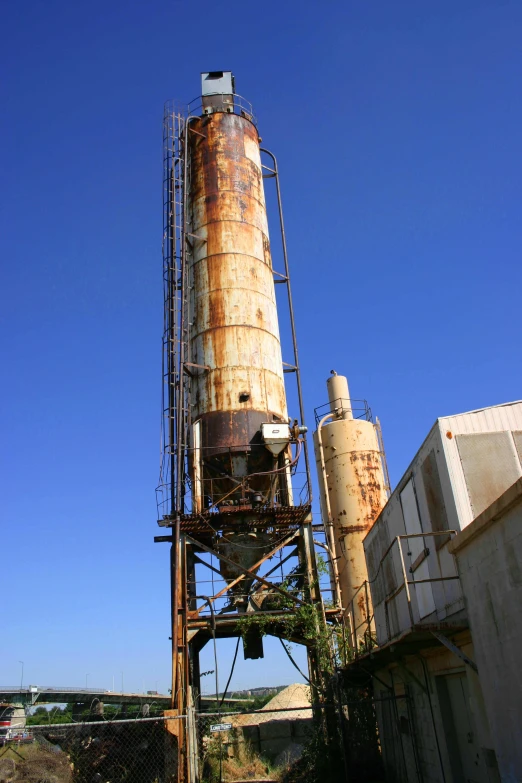 a large steel silo sits on the ground next to a bridge