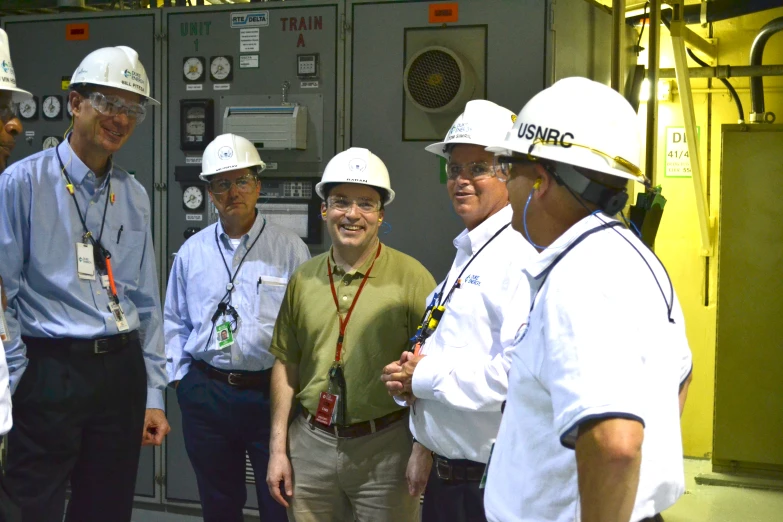 several men in hard hats standing around with controls on the wall
