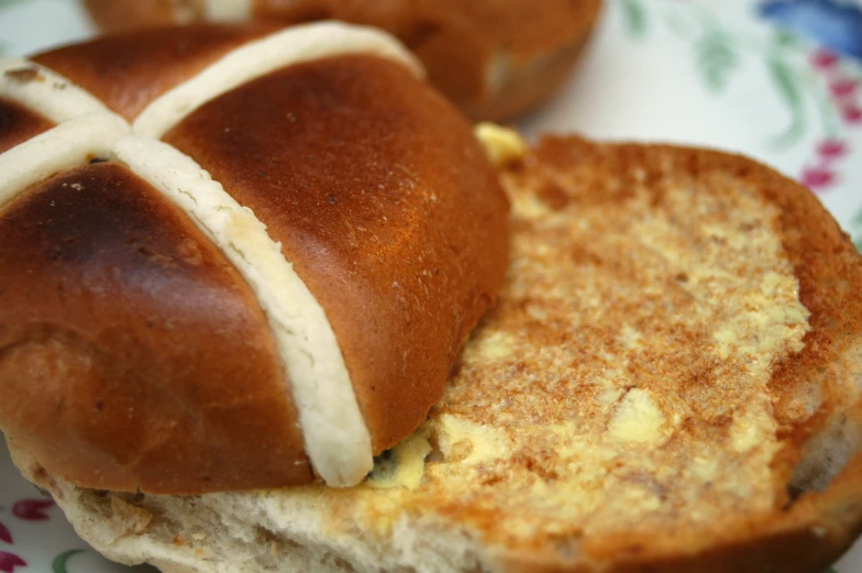 two rolls are on a flowered plate with two other sandwiches