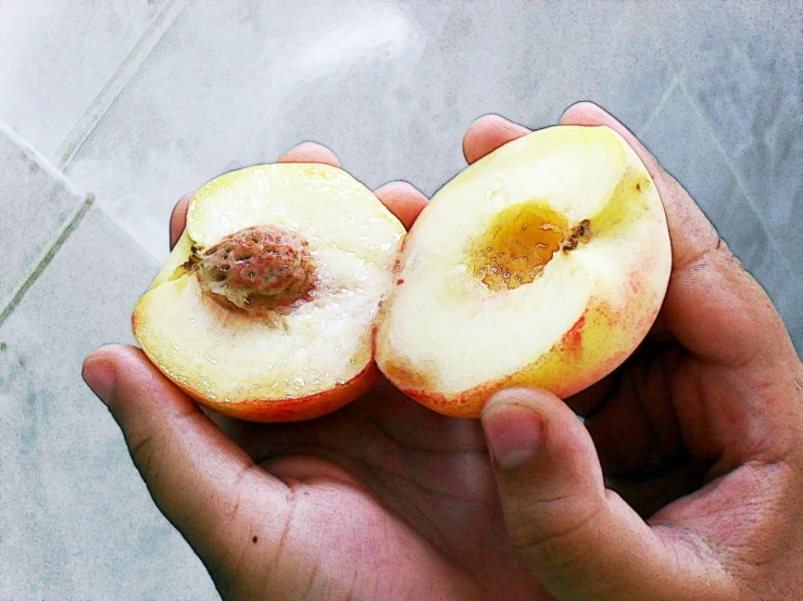 someone is holding half of a peach on their hand