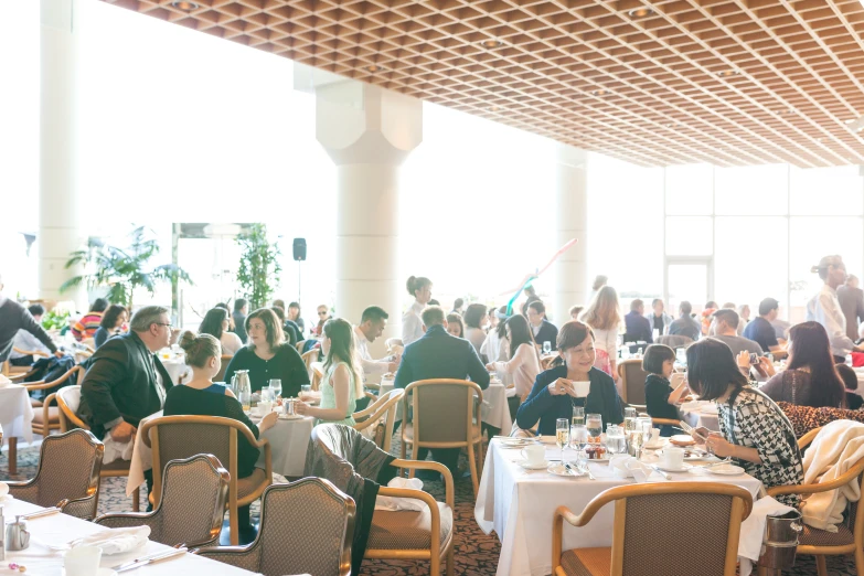 a room full of people seated at tables in a restaurant