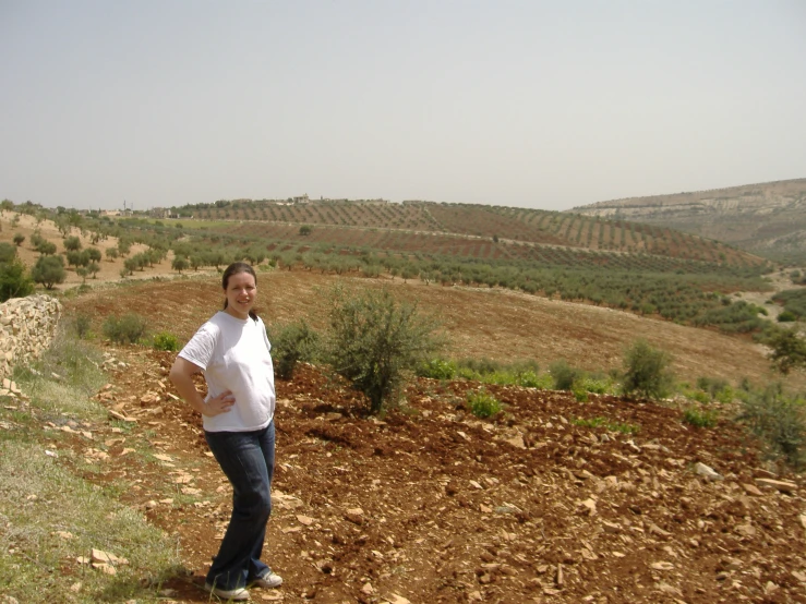 a lady standing on top of a dirt hillside