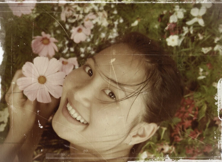 a girl that is smiling next to some flowers