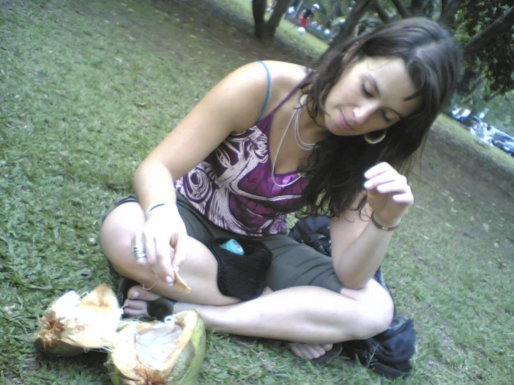 a young woman sitting on grass making a sign with her finger