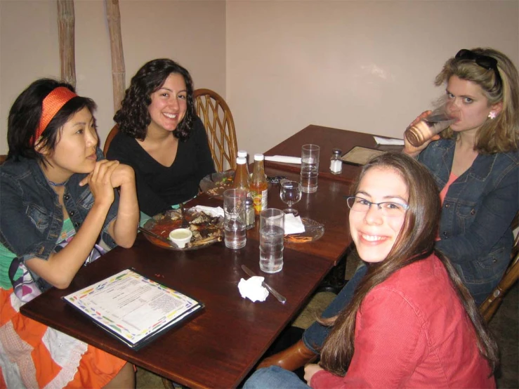 three women sitting at a table with drinks in each hand