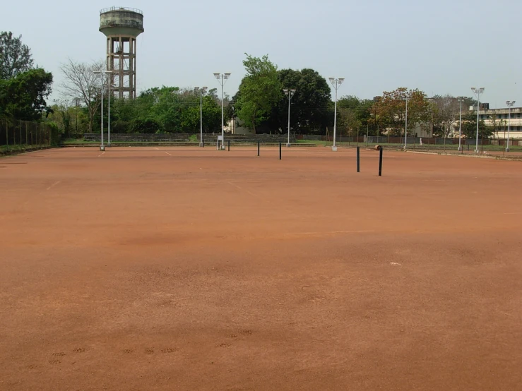 a tennis court has several rackets and trees near it