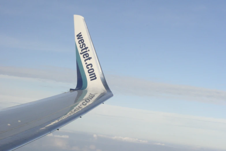 looking down on the wing of an airplane that has the word westexcolor written on the tail end