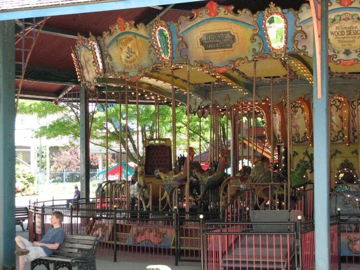 the people are sitting at the merry go round
