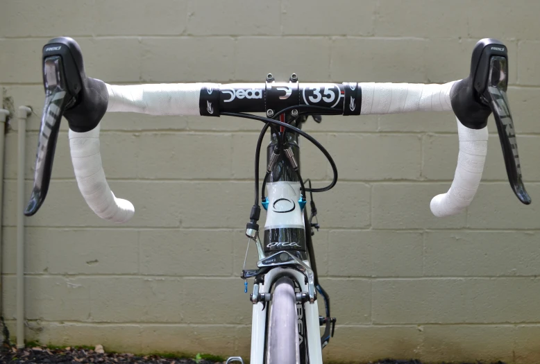 the front of a bike with handlebars, parked in front of a brick wall