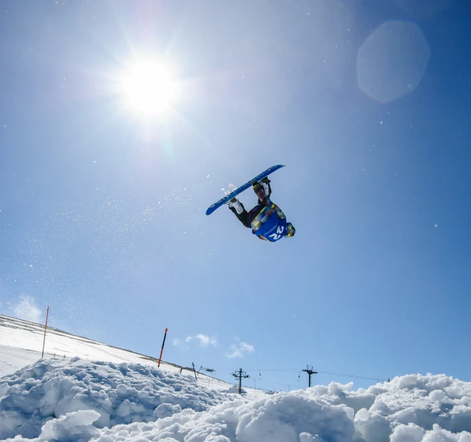 snowboarder in mid air after performing on sunny day