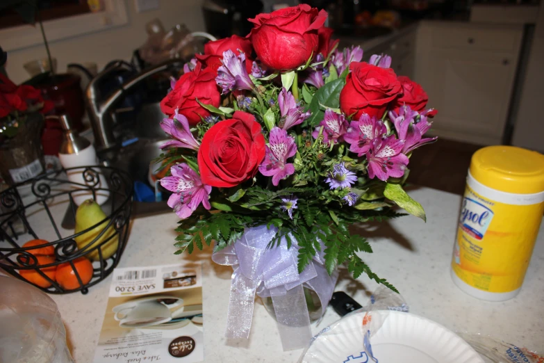 this is a vase of roses with purple flowers on the table