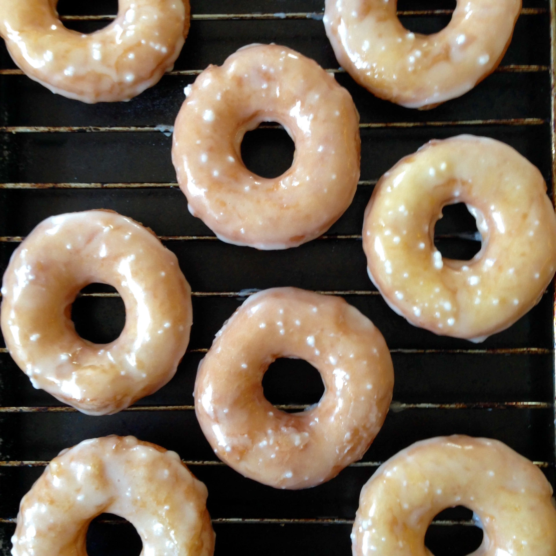 nine glazed doughnuts on a cooling rack