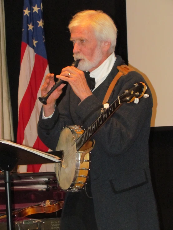 a man in suit with white hair singing into a microphone