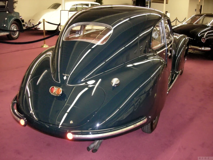 an old black car sits parked inside of the museum