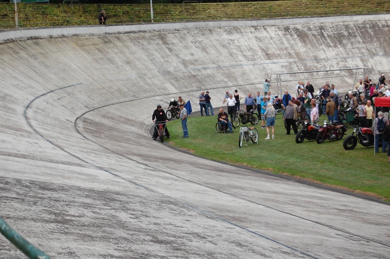 a crowd gathers around a motor cycle race track