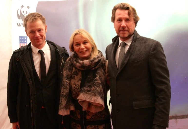 three people standing next to each other in front of a poster