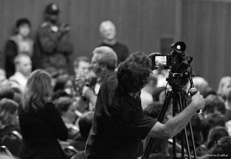 people in the audience with cameras at a meeting