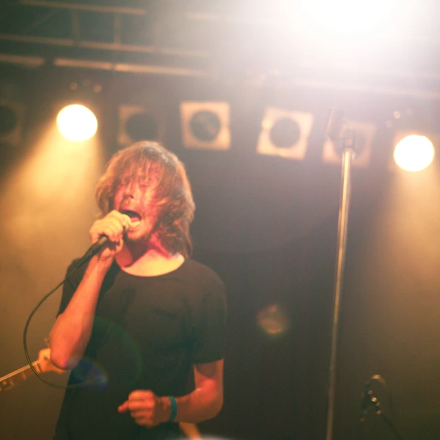 a woman singing into a microphone while holding a guitar