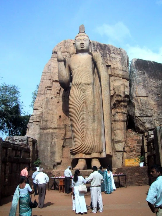 several people are standing around an ancient statue