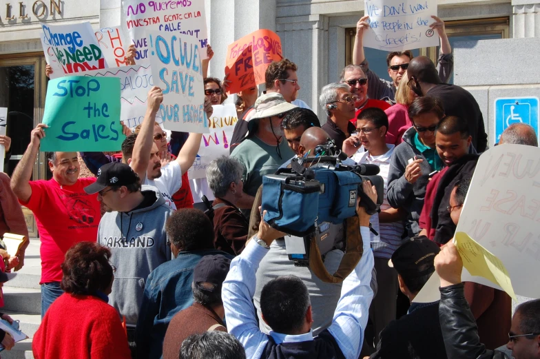 a large group of people hold signs and gesture signs